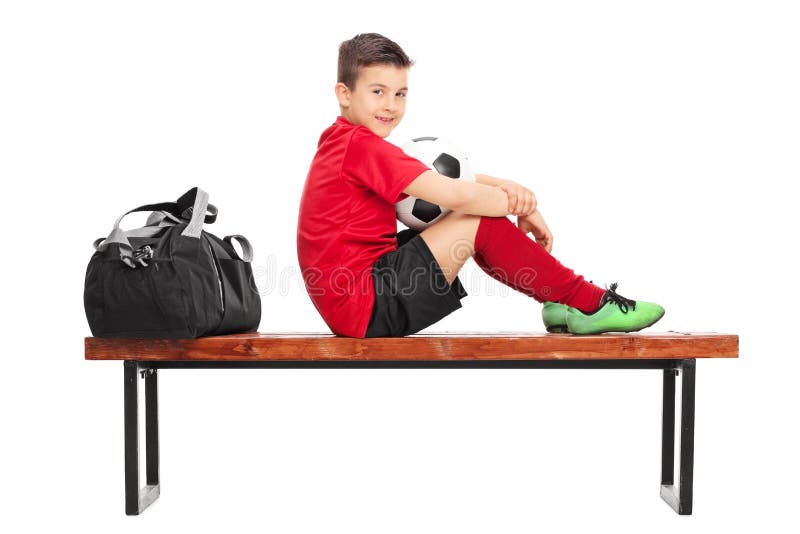 Jugador de fútbol menor que se sienta en un banco de madera fotografía de archivo Jugador de fútbol menor que se sienta en un banco de madera fotografía de archivo