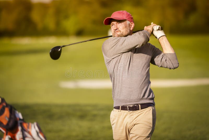Jugador de golf masculino que junta con te apagado con el club foto de archivo libre de regalías Jugador de golf masculino que junta con te apagado con el club foto de archivo libre de regalías