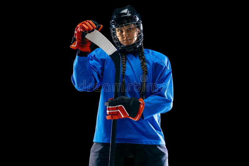 Jugador de hockey femenino joven con el palillo aislado en fondo negro imagenes de archivo Jugador de hockey femenino joven con el palillo aislado en fondo negro imagenes de archivo