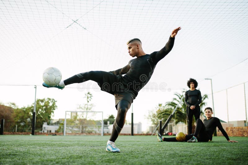 Jugador que golpea el balón de fútbol con el pie en campo