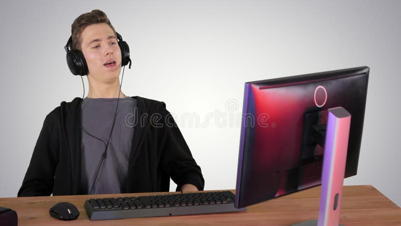 Jugador tipo en auriculares jugando videojuegos en el ordenador y ganar en el fondo degradado. almacen de metraje de vídeo