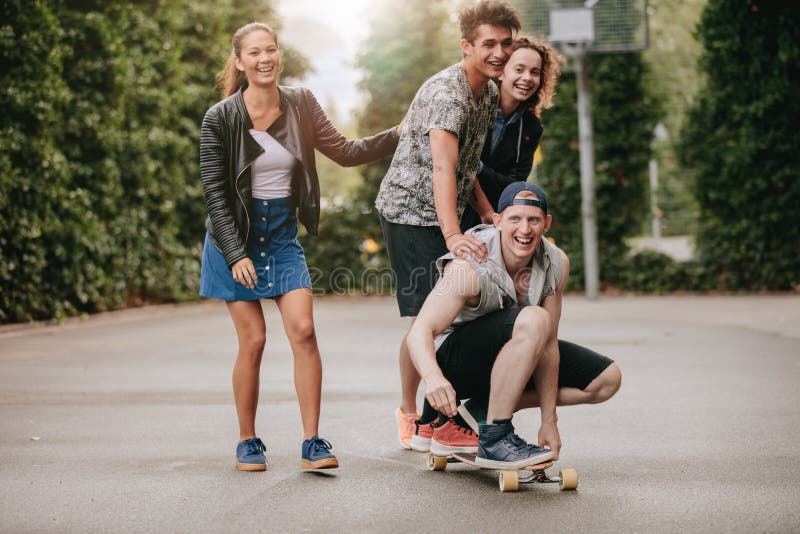 Jugendkerle auf Skateboard mit Mädchen lizenzfreie stockbilder Jugendkerle auf Skateboard mit Mädchen lizenzfreie stockbilder