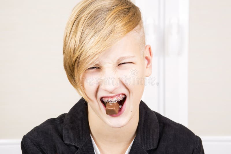 Jugendlich mit Klammern auf seinen Zähnen isst Schokolade stockfoto Jugendlich mit Klammern auf seinen Zähnen isst Schokolade stockfoto