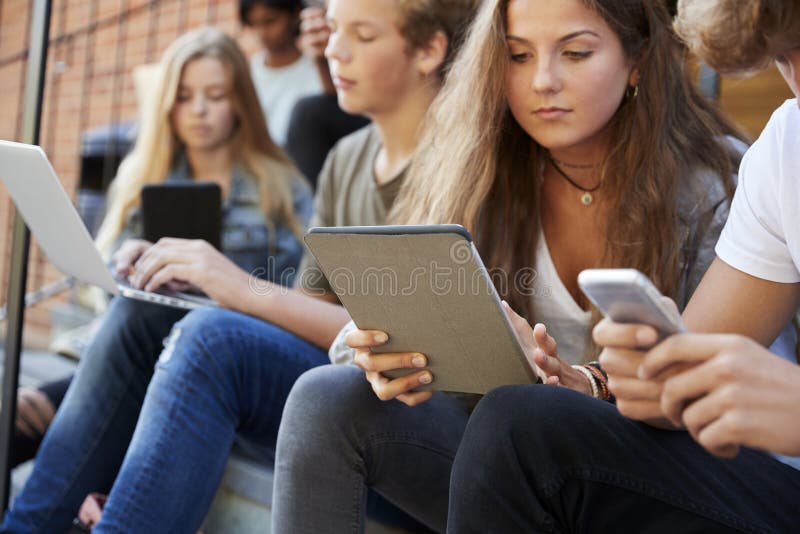 Jugendliche, die digitale Geräte auf dem Campus des College nutzen
