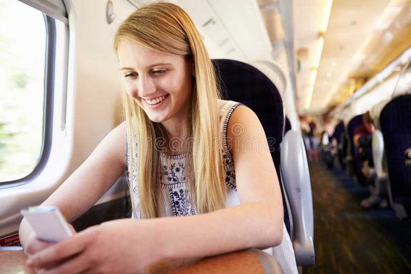 Jugendliche, die Handy auf Zug-Reise verwendet lizenzfreie stockfotos Jugendliche, die Handy auf Zug-Reise verwendet lizenzfreie stockfotos