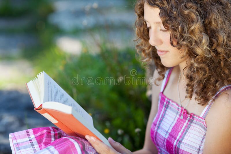 Jugendliche mit dem gelockten Haar ein Buch lesend stockfotografie Jugendliche mit dem gelockten Haar ein Buch lesend stockfotografie
