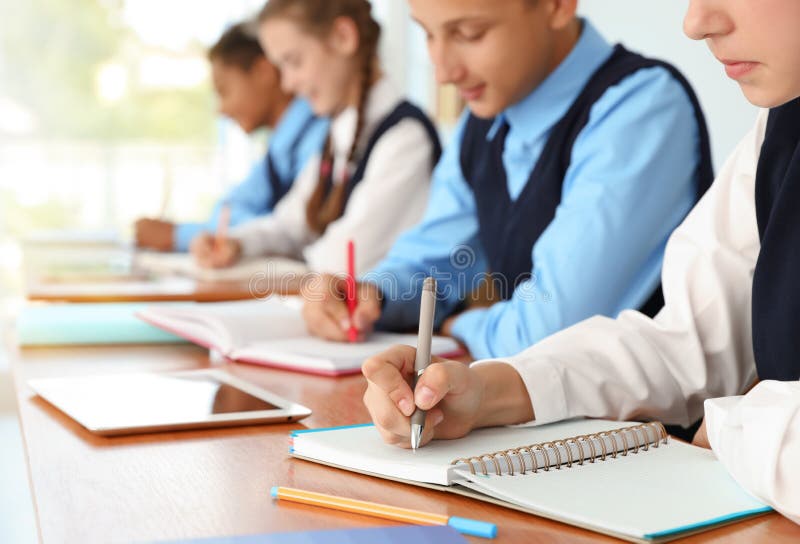 Jugendstudenten in der stilvollen Schuluniform am Schreibtisch, stockbild Jugendstudenten in der stilvollen Schuluniform am Schreibtisch, stockbild