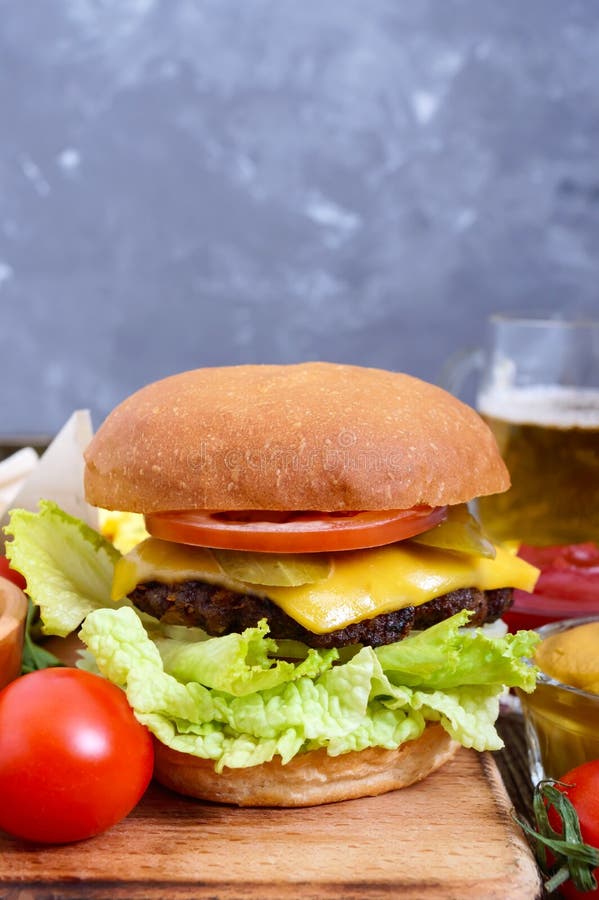 Juicy burger, τηγανιτές πατάτες, σάλτσες, μπύρα σε ένα ξύλινο υπόβαθρο Γρήγορο φαγητό στοκ εικόνες Juicy burger, τηγανιτές πατάτες, σάλτσες, μπύρα σε ένα ξύλινο υπόβαθρο Γρήγορο φαγητό στοκ εικόνες