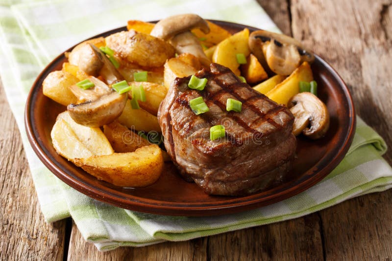 Juicy fillet mignon with fried potato wedges and mushrooms close
