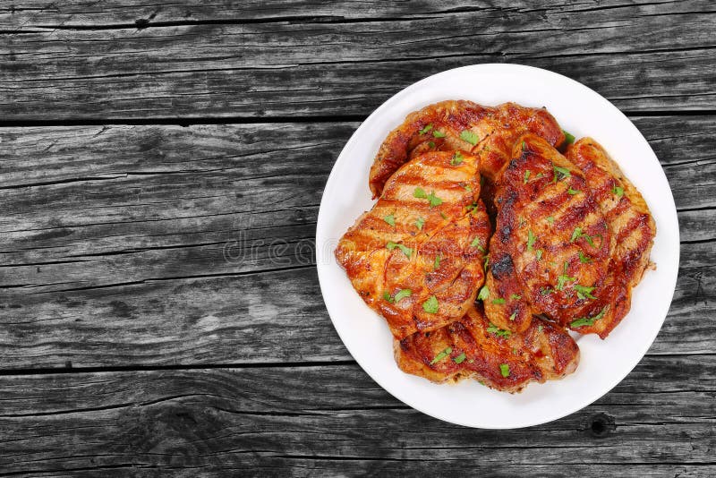 Incredibly juicy pork chops marinated in a honey, soy sauce and spices mixture, and grilled to a tender served on white plate on old rustic dark table, view from above, blank space left. Pork view stock images, royalty-free photos and pictures