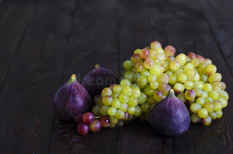 Juicy yellow, green raisins and several ripe blue figs on a dark wooden background. fresh fruits, natural vitamin, vegetarian food stock photos Juicy yellow, green raisins and several ripe blue figs on a dark wooden background. fresh fruits, natural vitamin, vegetarian food stock photos