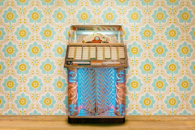 Colorful vintage jukebox in front of retro flower wallpaper on a wooden floor. Colorful vintage jukebox in front of retro flower wallpaper on a wooden floor