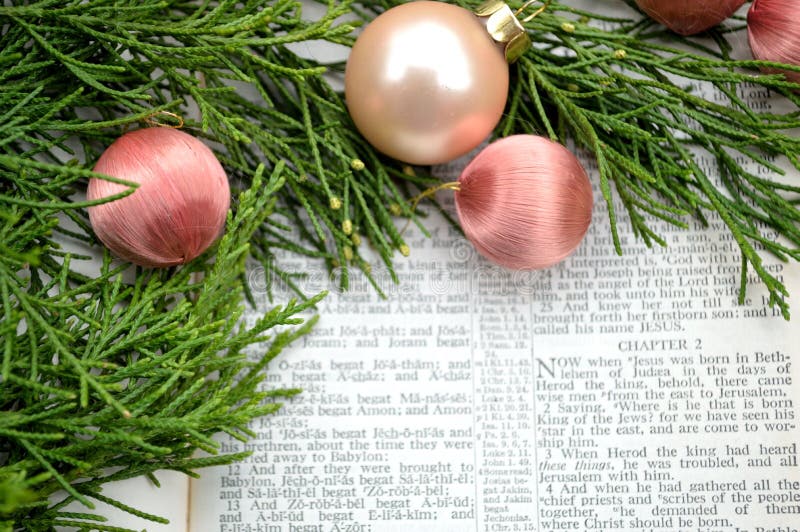 The Christmas story, as told in the Gospel of Matthew Chapter 2, open Bible with cedar greenery and antique pink silk ornaments. The Christmas story, as told in the Gospel of Matthew Chapter 2, open Bible with cedar greenery and antique pink silk ornaments.