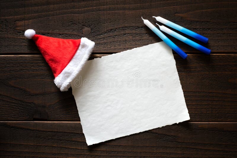 Jul eller kort för Chrismukkah feriepapper med röda och vita Santa Claus Hat och Chanukkahstearinljus på den mörka lantliga träta