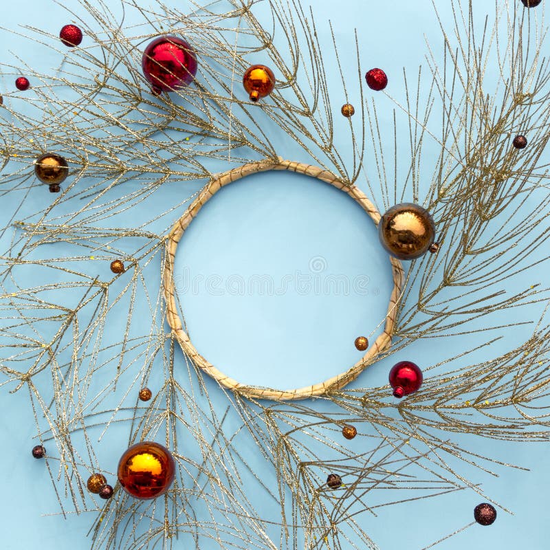 Jul eller vintersammansättning för nytt år Rund ram som göras av guld- trädfilialer och röda dekorativa julprydnader på blått arkivbild Jul eller vintersammansättning för nytt år Rund ram som göras av guld- trädfilialer och röda dekorativa julprydnader på blått arkivbild