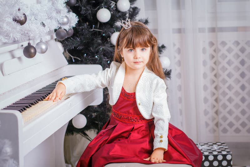 Julbarnliten flicka som hemma spelar på piano royaltyfri bild Julbarnliten flicka som hemma spelar på piano royaltyfri bild