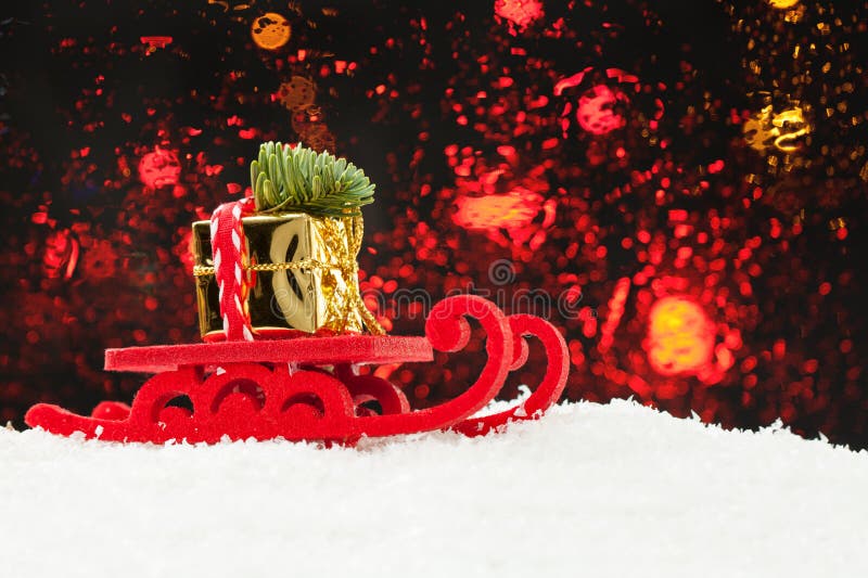 Julfilial och klockor Jultomtensläde som kör den guld- gåvan och Xmas-trädet mot abstrakt bokehljusbakgrund royaltyfria bilder Julfilial och klockor Jultomtensläde som kör den guld- gåvan och Xmas-trädet mot abstrakt bokehljusbakgrund royaltyfria bilder