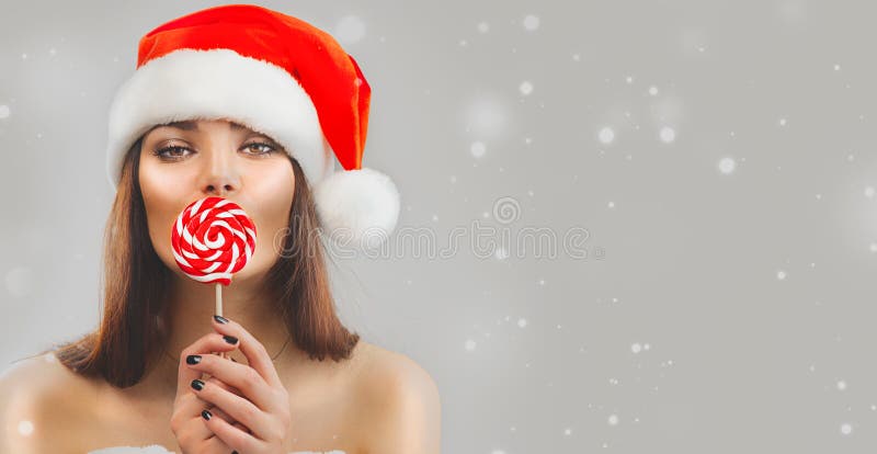 Julkvinna Bladmodellflicka i Santa Claus-hatt med röda xmas lollipop-godis, gåva Försäljning Uttryck som överraskats arkivbilder