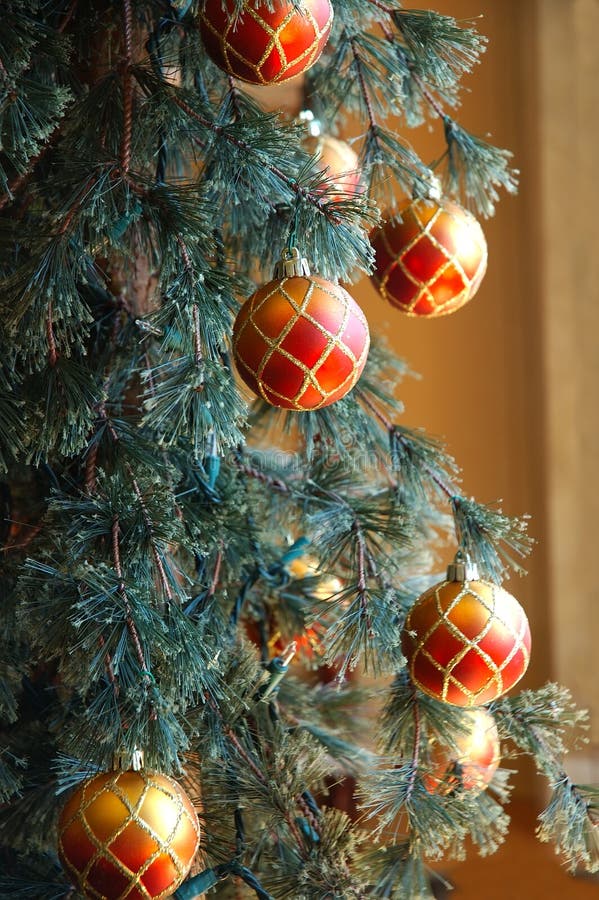 Red and gold glittery ornaments hang on the branches of a Christmas tree. Red and gold glittery ornaments hang on the branches of a Christmas tree.