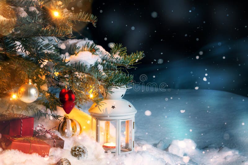 Julsammansättning - gåvor och en lykta i snön under en julgran som dekoreras med ljus och julgranen royaltyfri fotografi Julsammansättning - gåvor och en lykta i snön under en julgran som dekoreras med ljus och julgranen royaltyfri fotografi