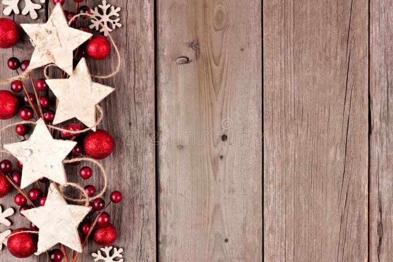 Rustic Christmas side border with wood star ornaments and baubles on an aged wood background. Rustic Christmas side border with wood star ornaments and baubles on an aged wood background