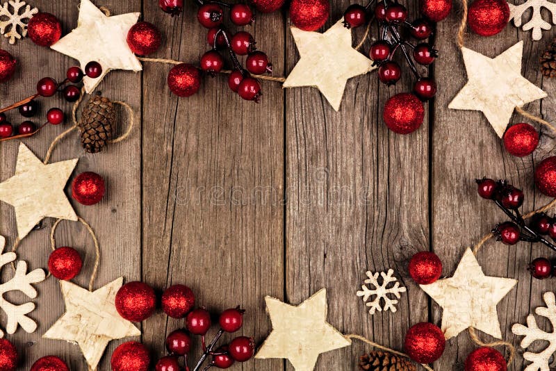 Christmas frame with wood star ornaments and red baubles. Overhead view on an rustic wood background. Christmas frame with wood star ornaments and red baubles. Overhead view on an rustic wood background