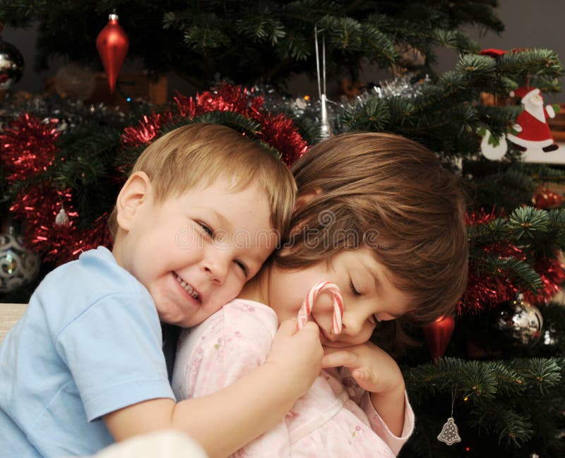 A portrait of two sisters hugging next to a Christmas tree. A portrait of two sisters hugging next to a Christmas tree.