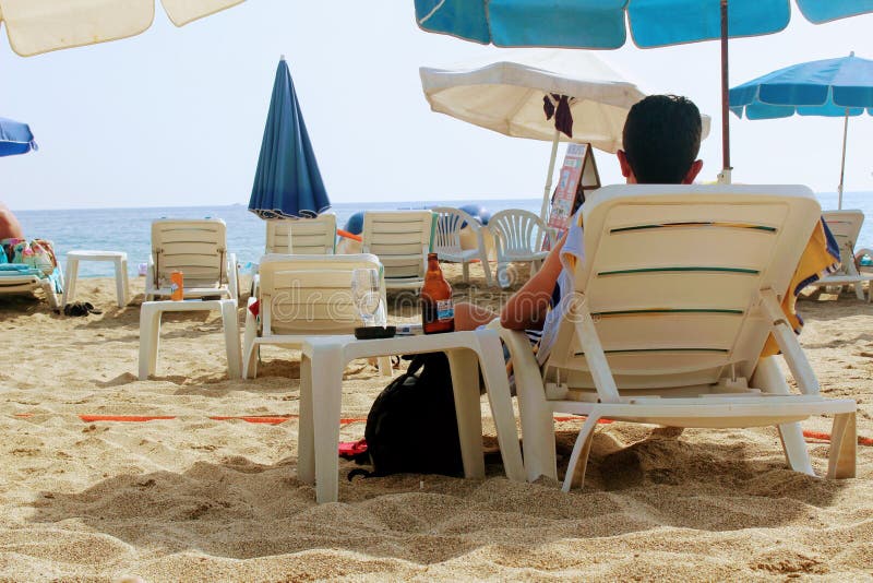 July, 2017 - A man is resting with a bottle of beer lying on a sunbed on Cleopatra Beach Alanya, Turkey stock image July, 2017 - A man is resting with a bottle of beer lying on a sunbed on Cleopatra Beach Alanya, Turkey stock image