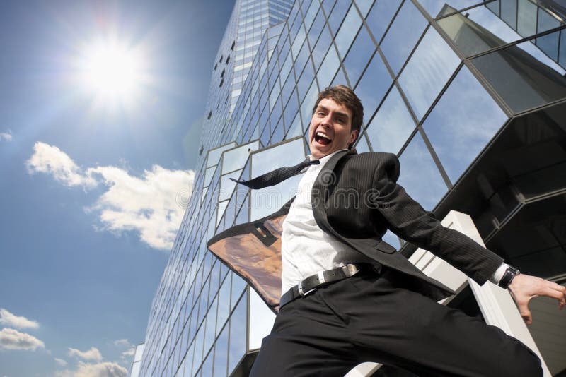 Feliz joven exitoso hombre saltando contra oficina.