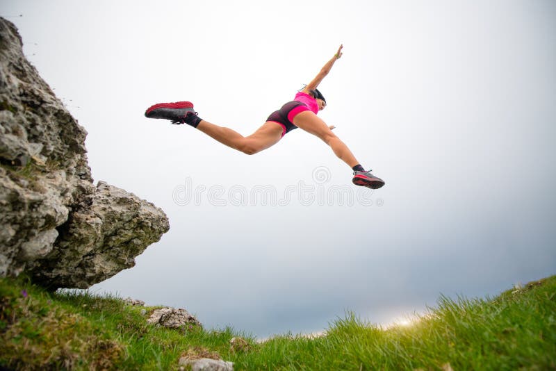 Jump of a sporty woman athlete running in the mountains