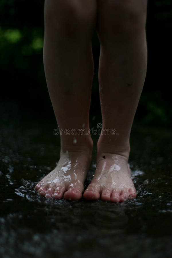 A kid having loads of fun jumping in mud puddle