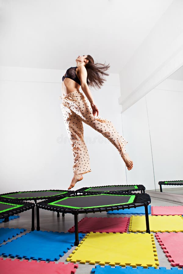 Jumping young woman on a trampoline stock image.