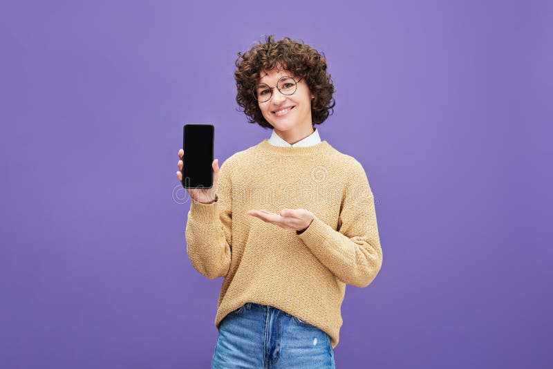 Jung fröhliche Brunette-Frau zeigt Werbung auf Smartphone stockbild