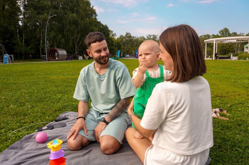 Jung Mutter und Vater sind glücklich, mit ihrer kleinen Tochter auf einem Picknick zu kommunizieren. Familienurlaub