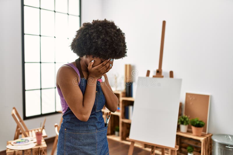 Young african american woman with afro hair at art studio with sad expression covering face with hands while crying. depression concept. Young african american woman with afro hair at art studio with sad expression covering face with hands while crying. depression concept