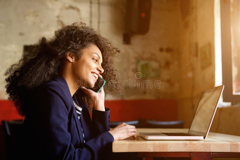 Junge afrikanische Frau, die im Café sich entspannt und Telefonanruf macht