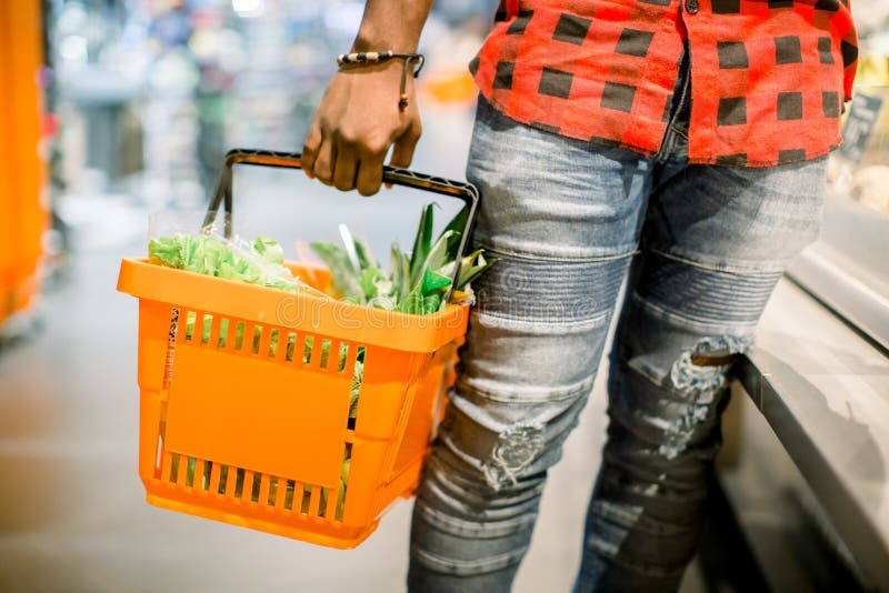 Young african man buying vegetables and fruits in grocery section at supermarket. Black man choose vegetables and fruits in the supermarket while holding grocery basket. Man shopping veggies at supermarket. Young african man buying vegetables and fruits in grocery section at supermarket. Black man choose vegetables and fruits in the supermarket while holding grocery basket. Man shopping veggies at supermarket.