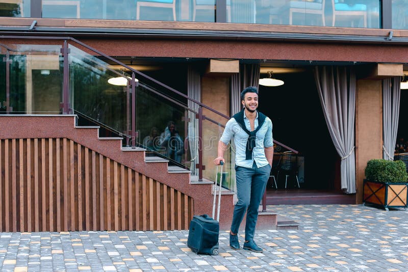Junge Araber Geschäftsmann Student kam in das Restaurant mit Koffer in der Hand lächelnd an Kamerafahrten und schaut weg. lizenzfreies stockfoto