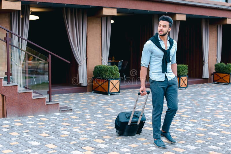 Junge Araber Geschäftsmann Student kam in das Restaurant mit Koffer in der Hand lächelnd an Kamerafahrten und schaut weg. lizenzfreie stockfotografie