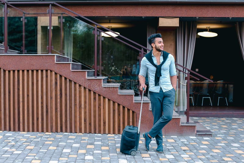 Junge Araber Geschäftsmann Student kam in das Restaurant mit Koffer in der Hand lächelnd an Kamerafahrten und schaut weg. lizenzfreie stockbilder