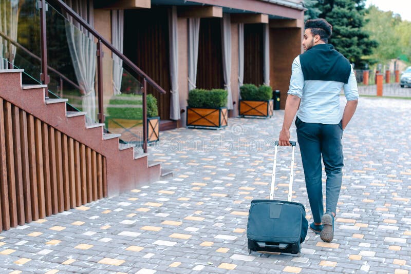 Junge Araber Geschäftsmann Student kam in das Restaurant mit Koffer in der Hand lächelnd an Kamerafahrten und schaut weg. lizenzfreie stockfotografie