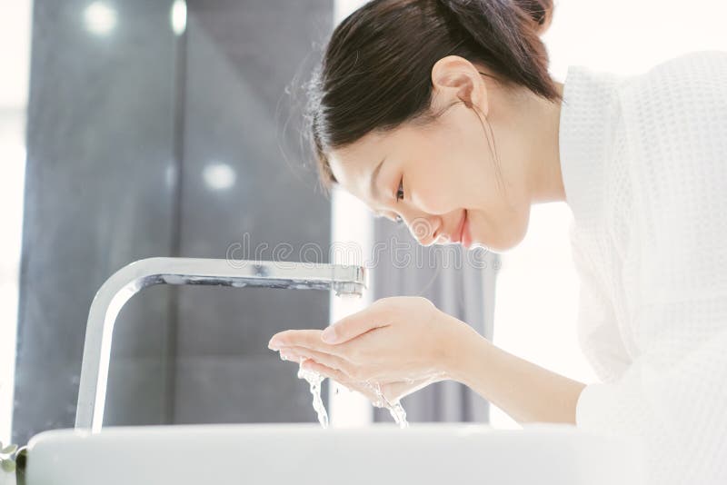Junge Asiatin, die ihr Gesicht wäscht lizenzfreies stockfoto