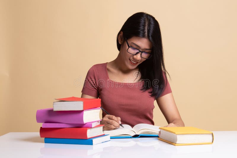 Junge Asiatin las ein Buch mit B?chern auf Tabelle stockbilder Junge Asiatin las ein Buch mit B?chern auf Tabelle stockbilder