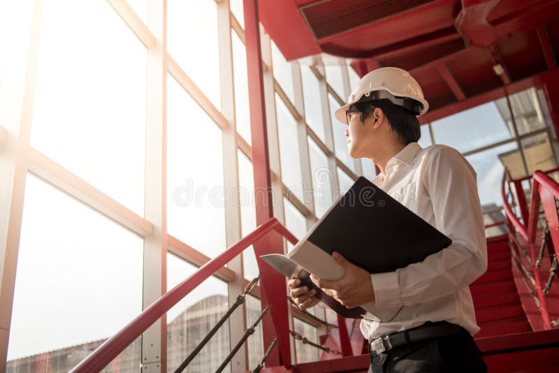 Junge asiatische Ingenieurholdingdateien an der Baustelle lizenzfreies stockbild Junge asiatische Ingenieurholdingdateien an der Baustelle lizenzfreies stockbild