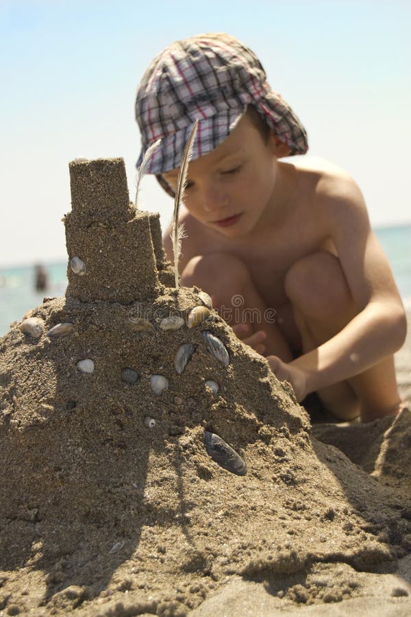 Junge auf dem Strand, der Sandburg macht