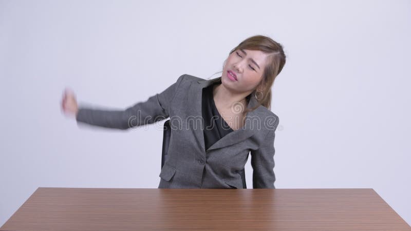Junge betonten die asiatische Geschäftsfrau, die Nackenschmerzen am Schreibtisch hat