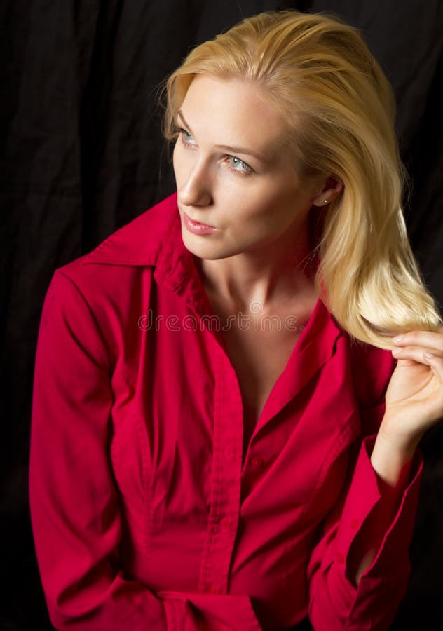 Classy young blond woman twisting her hair poses in red blouse. Classy young blond woman twisting her hair poses in red blouse