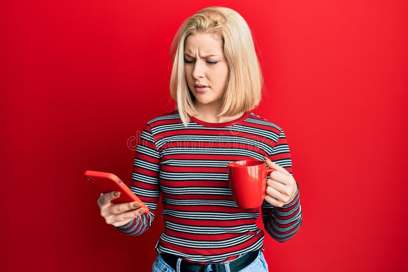 Young blonde woman using smartphone and drinking a cup of coffee clueless and confused expression. doubt concept. Young blonde woman using smartphone and drinking a cup of coffee clueless and confused expression. doubt concept