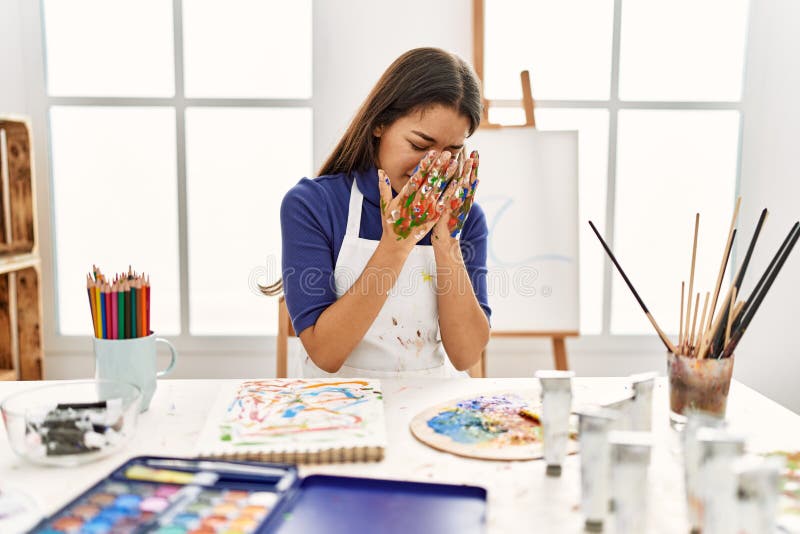 Young brunette woman at art studio with painted hands with sad expression covering face with hands while crying. depression concept. Young brunette woman at art studio with painted hands with sad expression covering face with hands while crying. depression concept