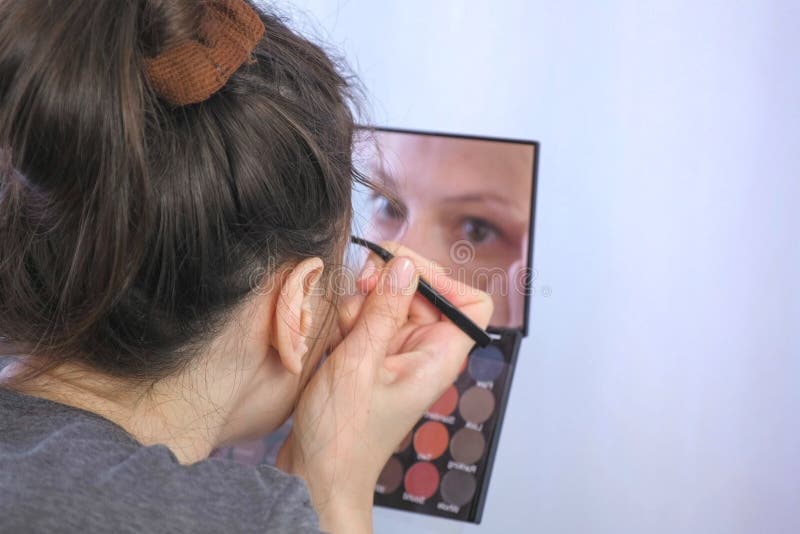 Junge brunette Frau zupft ihre Augenbrauen mit Pinzette vor dem Spiegel zu Hause stockfotos Junge brunette Frau zupft ihre Augenbrauen mit Pinzette vor dem Spiegel zu Hause stockfotos
